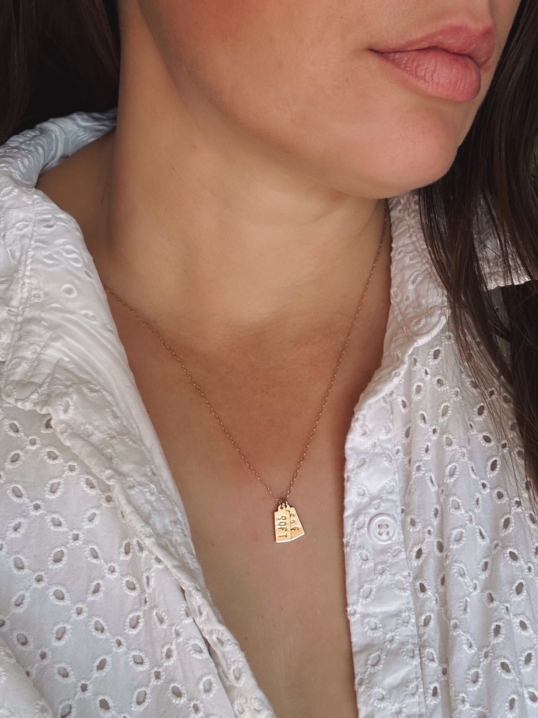 Close-up of a person wearing a 14k gold filled necklace with a pendant against a white blouse.